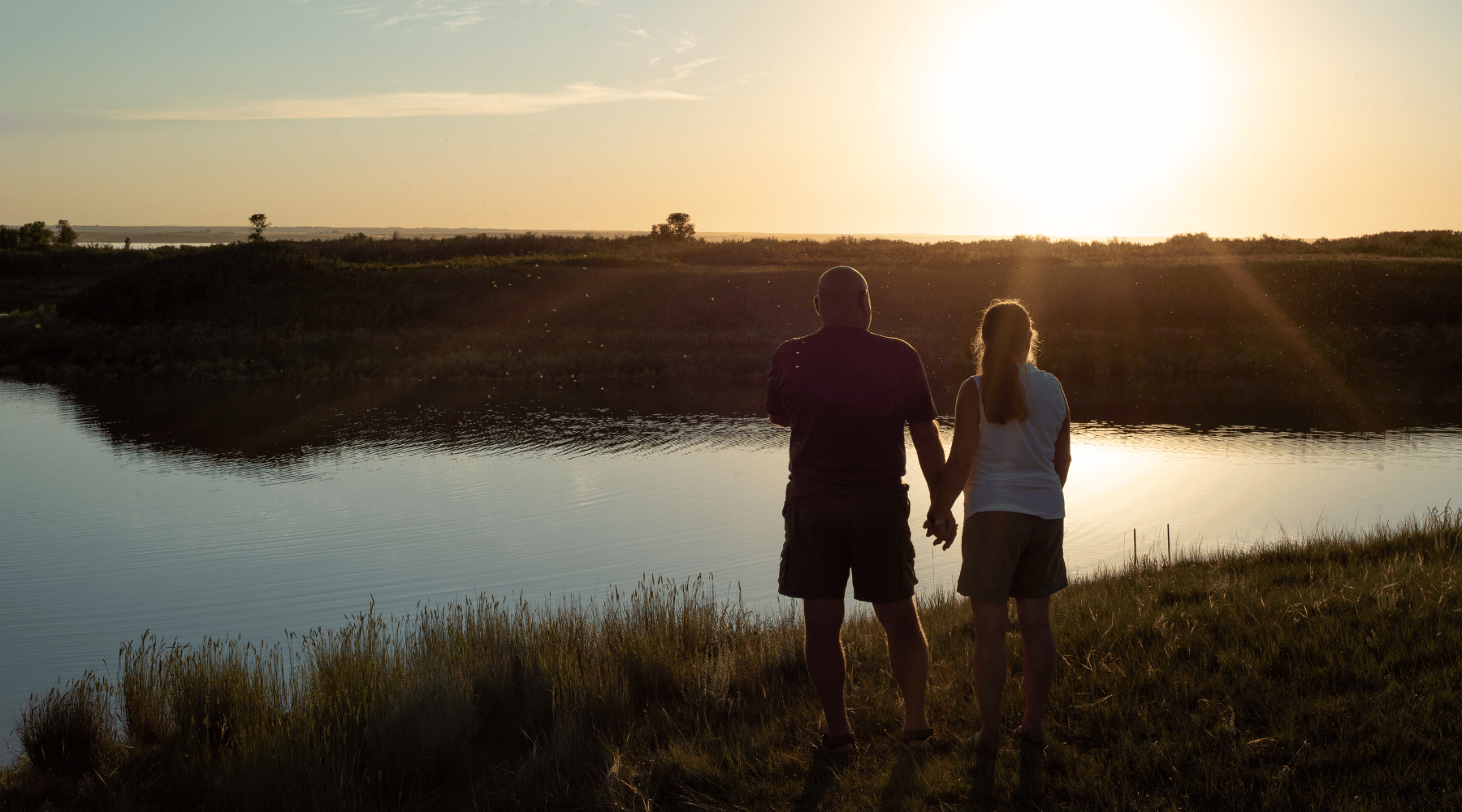 Couple standing watching the sunset by the beach at Lake Diefenbaker